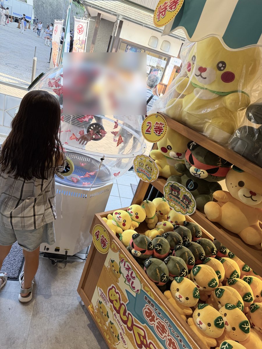 道後温泉本館のすぐ横のお店でぬいぐるみくじに挑戦する子ども