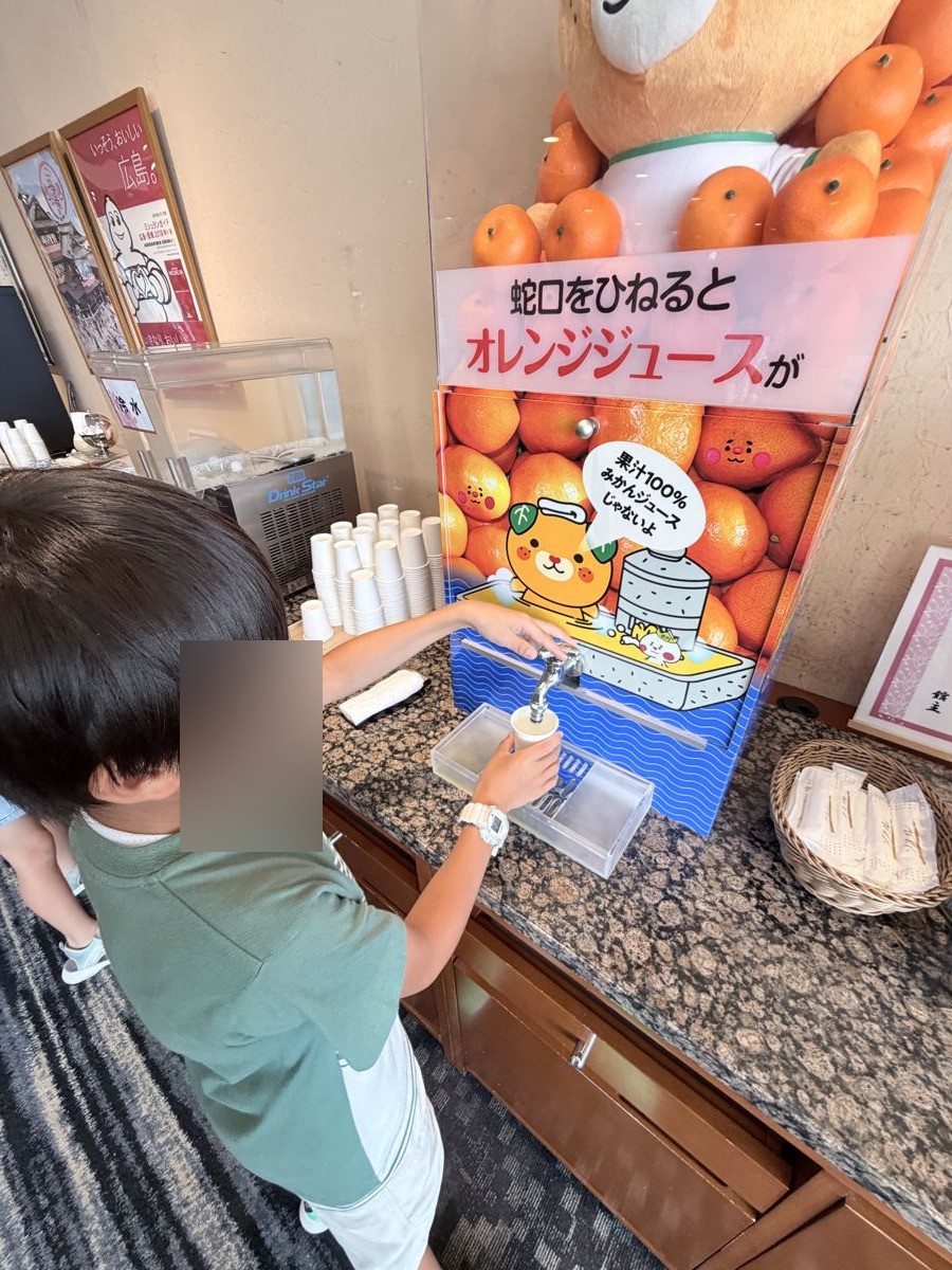 道後プリンスホテルの蛇口オレンジジュースをコップに注ぐ子ども