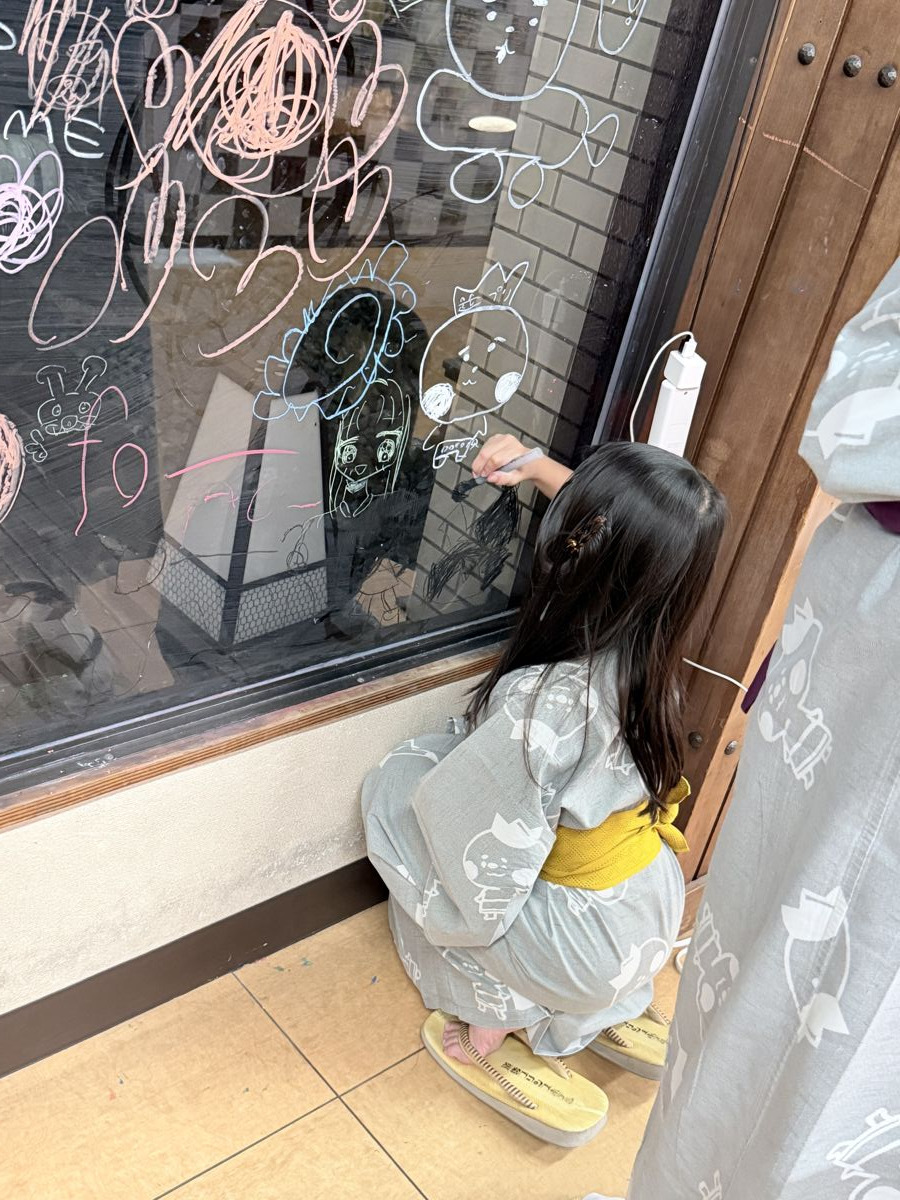 道後プリンスホテルの売店横にあるらくがき壁に絵を描く子ども