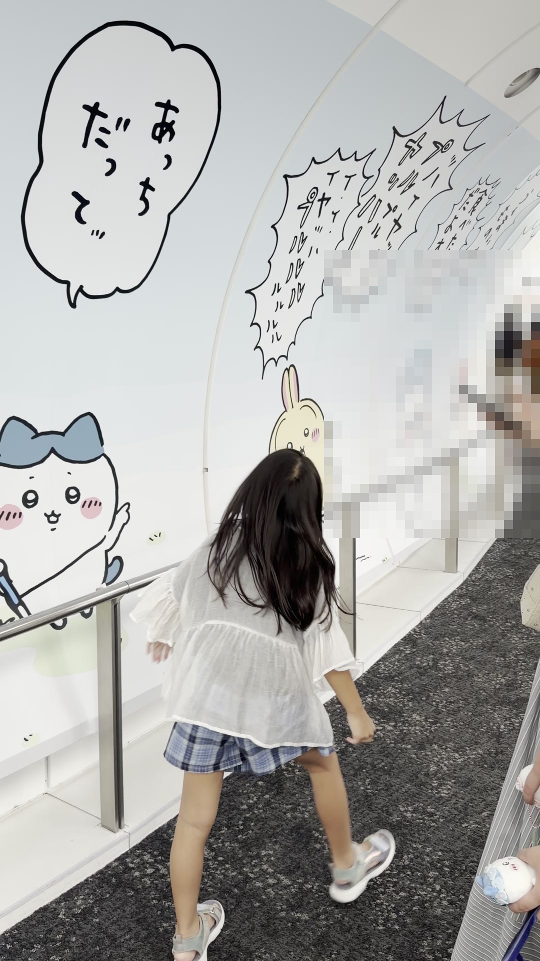 天望回廊450mの壁一面に描かれたちいかわの装飾の前を歩く子どもの後ろ姿