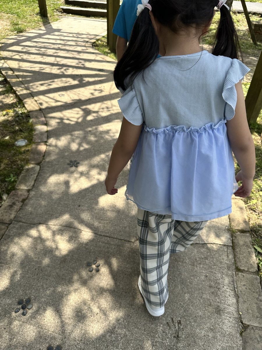 動物の足あとの模様が入った石畳を歩く女の子の足元